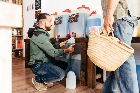 Tendero rellena envase de cliente en tienda a granel. El comercio sostenible es un gran emprendimiento en México